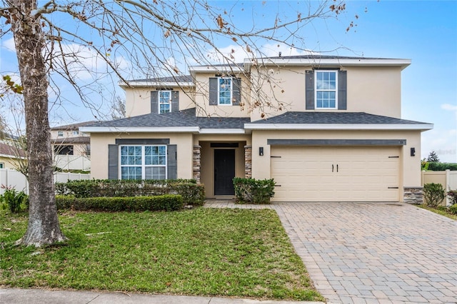 traditional-style home featuring decorative driveway, roof with shingles, stucco siding, a front yard, and a garage