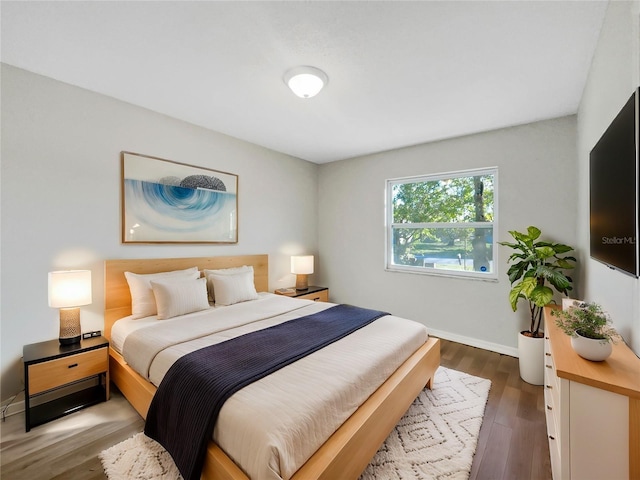 bedroom with baseboards and dark wood-type flooring