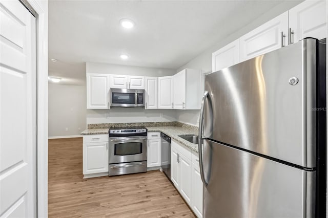 kitchen with light stone counters, recessed lighting, stainless steel appliances, light wood-style floors, and white cabinets
