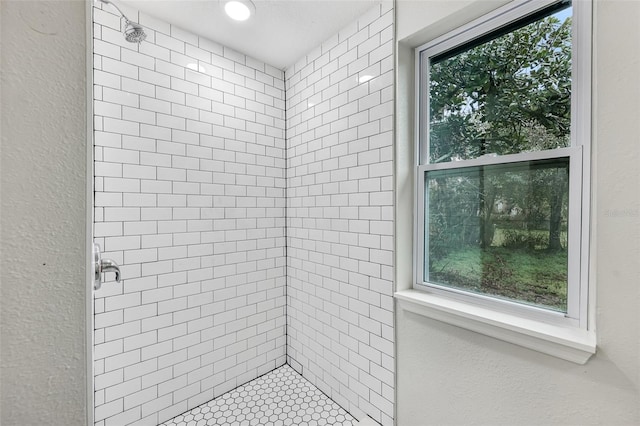 bathroom with a textured wall and a tile shower