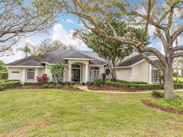 view of front facade featuring a front yard, french doors, roof with shingles, and stucco siding