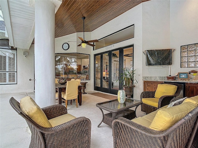 living area featuring carpet, a textured wall, a towering ceiling, a ceiling fan, and wood ceiling