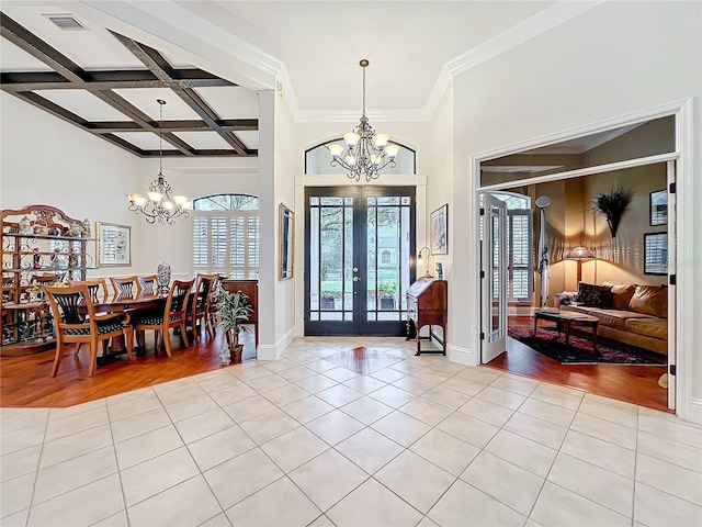 foyer with french doors, light tile patterned flooring, coffered ceiling, and a notable chandelier