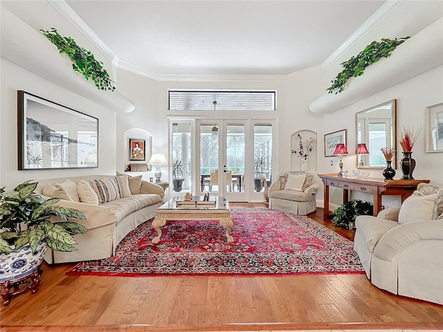 living area featuring a healthy amount of sunlight, wood-type flooring, crown molding, and french doors