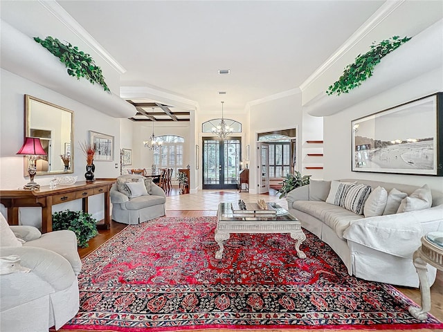 living area featuring a chandelier, wood finished floors, visible vents, french doors, and ornamental molding