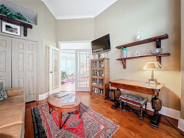 interior space with ornamental molding, wood finished floors, a high ceiling, and baseboards