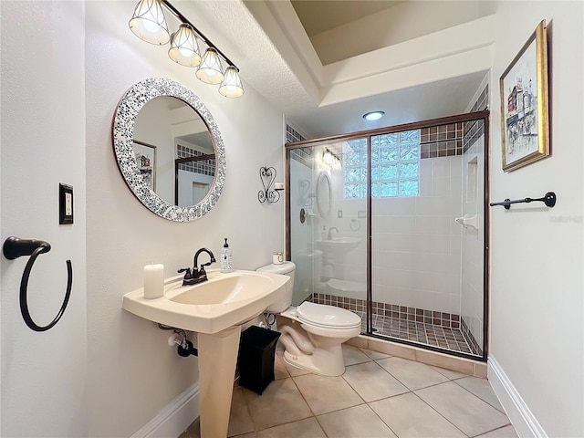 bathroom with baseboards, a shower stall, toilet, and tile patterned floors