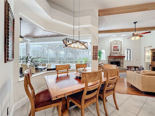 dining space featuring light tile patterned floors, ceiling fan, a fireplace, and baseboards