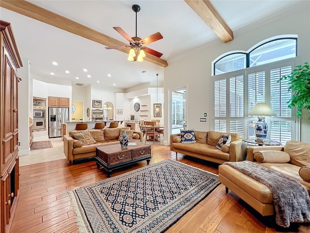 living room with a ceiling fan, beam ceiling, crown molding, and light wood finished floors