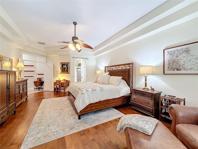 bedroom with a ceiling fan, visible vents, and hardwood / wood-style floors