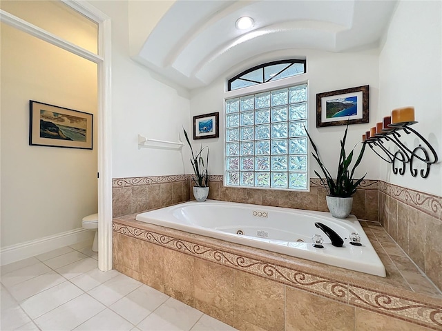 bathroom featuring toilet, vaulted ceiling, a whirlpool tub, baseboards, and tile patterned floors