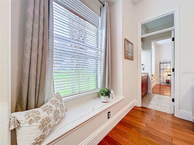 corridor with light wood-type flooring and baseboards