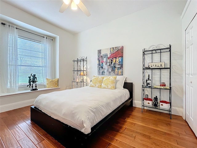 bedroom featuring a closet, ceiling fan, baseboards, and wood finished floors