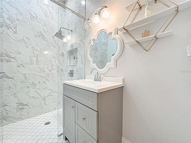 full bath featuring a textured wall, a walk in shower, and vanity