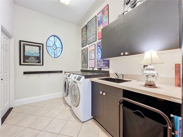 laundry room featuring washing machine and clothes dryer, cabinet space, light tile patterned flooring, a sink, and baseboards