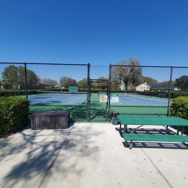 view of tennis court with a gate and fence