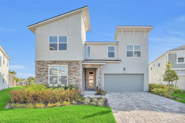 contemporary house featuring a garage, stone siding, decorative driveway, and stucco siding