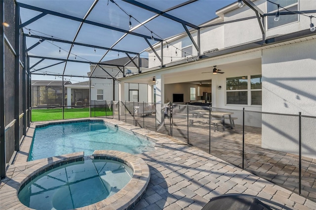 view of swimming pool featuring ceiling fan, glass enclosure, a patio, and a pool with connected hot tub