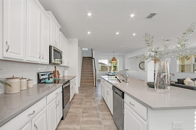 kitchen featuring a sink, visible vents, white cabinets, open floor plan, and appliances with stainless steel finishes