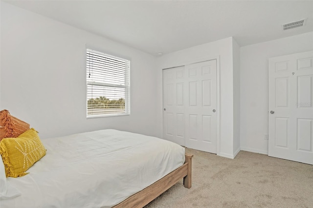 bedroom with baseboards, a closet, visible vents, and light colored carpet