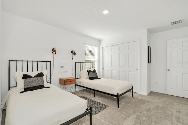 bedroom with light carpet, a closet, visible vents, and baseboards