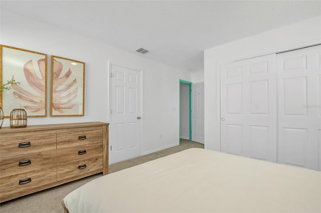 bedroom featuring a closet, light colored carpet, visible vents, and baseboards