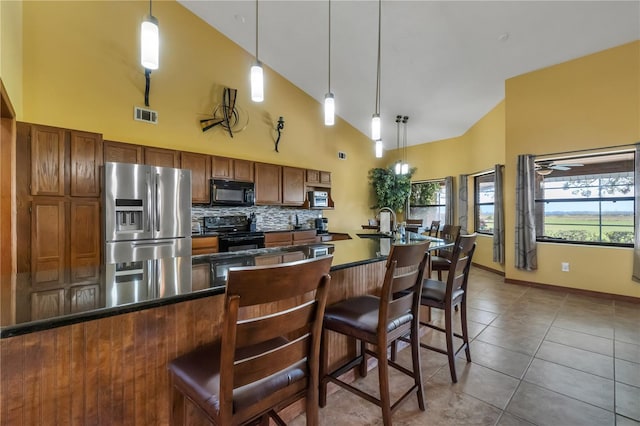 2825 Lake Tohopekaliga Blvd, Kissimmee, FL 34746 - kitchen with brown cabinets, dark countertops, visible vents, black appliances, and high vaulted ceiling