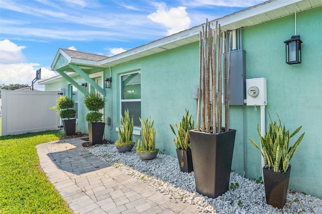 view of home's exterior with stucco siding and fence