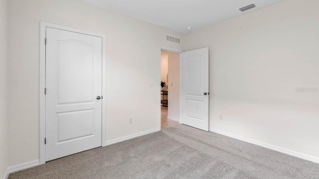 unfurnished bedroom featuring visible vents, light carpet, and baseboards