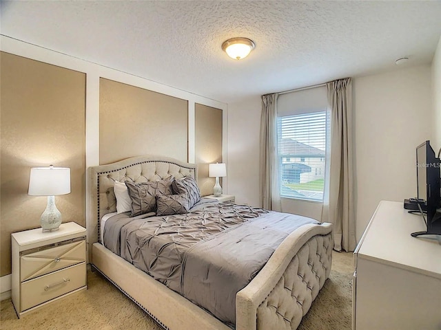 bedroom with a textured ceiling and light colored carpet