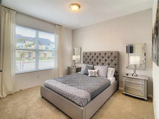 bedroom featuring light carpet, a textured ceiling, and baseboards