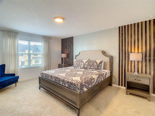 bedroom featuring light carpet, baseboards, and a textured ceiling