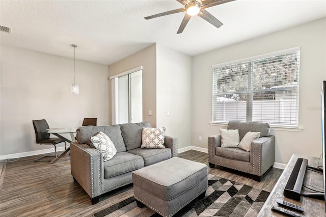 living room with dark wood-style floors, visible vents, ceiling fan, a textured ceiling, and baseboards