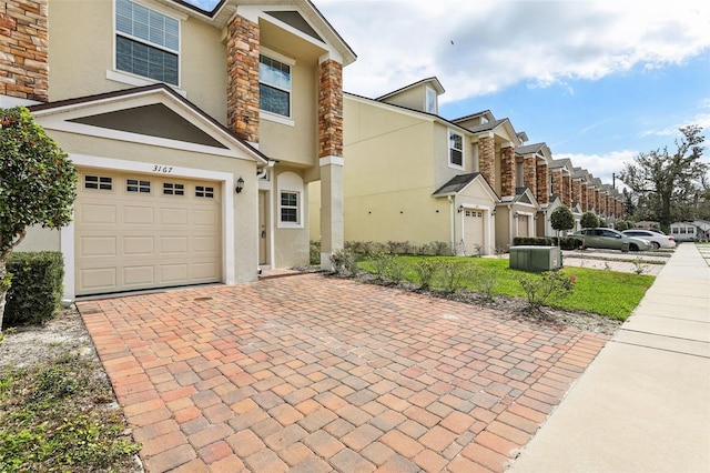 view of front of property with a residential view, decorative driveway, an attached garage, and stucco siding