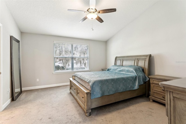 bedroom with light carpet, baseboards, a ceiling fan, vaulted ceiling, and a textured ceiling