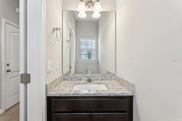 bathroom with a chandelier, wood finished floors, and vanity