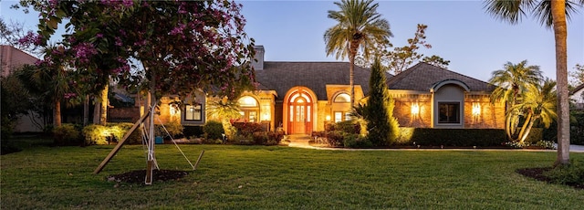 view of front of home featuring a chimney, a front yard, and stucco siding