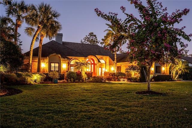 view of front of property featuring a lawn and a chimney