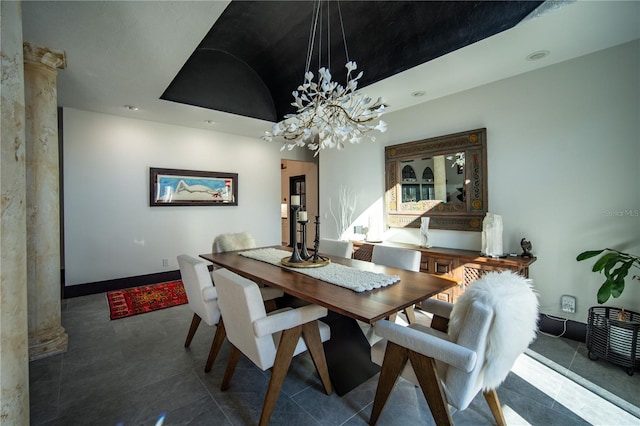 dining area with tile patterned flooring, a notable chandelier, baseboards, a raised ceiling, and ornate columns