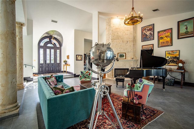 living room featuring visible vents, a towering ceiling, decorative columns, and baseboards