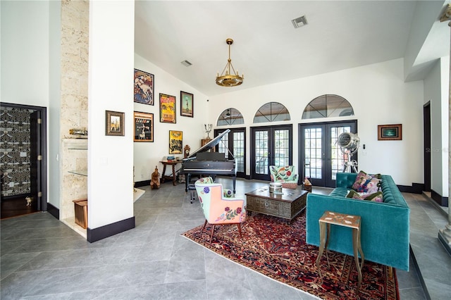 living area with high vaulted ceiling, french doors, visible vents, and baseboards