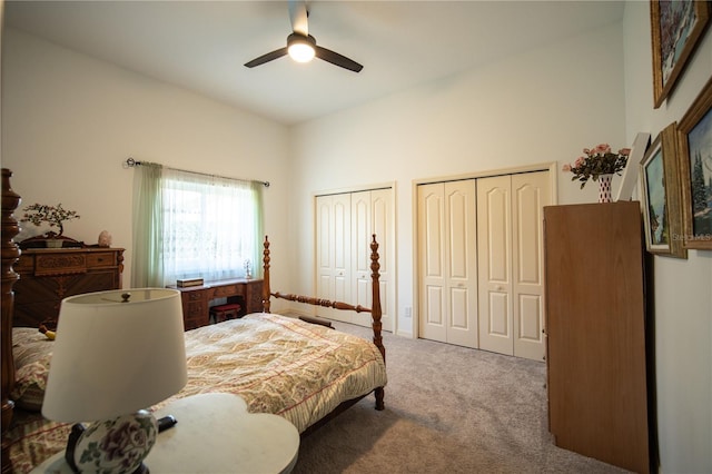 carpeted bedroom with high vaulted ceiling, a ceiling fan, and multiple closets