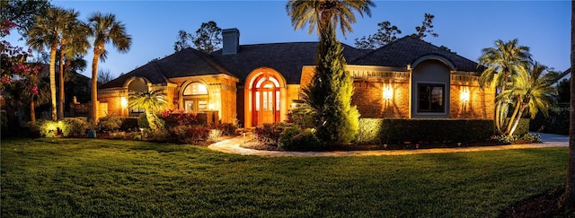 view of front of home with a chimney and a front lawn