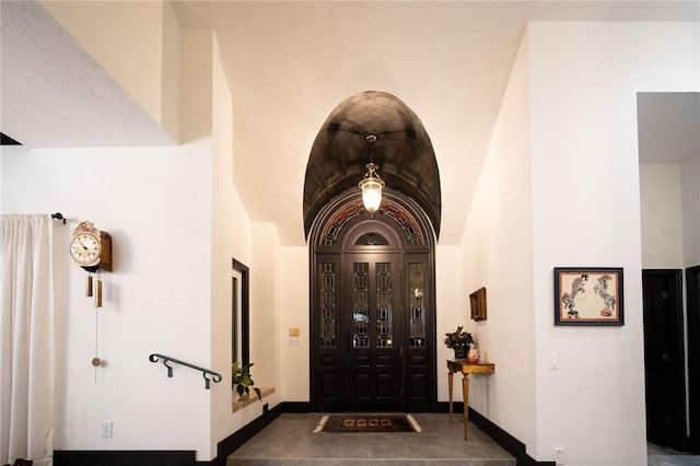 foyer entrance featuring high vaulted ceiling and baseboards