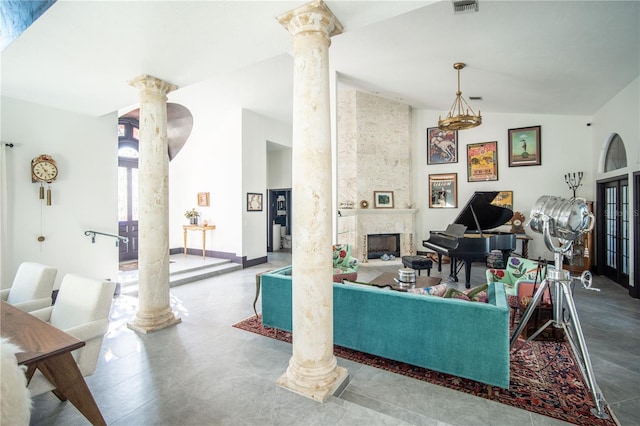 living room featuring lofted ceiling, visible vents, a large fireplace, and ornate columns