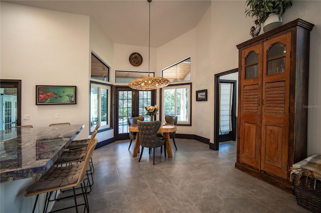 dining area with a high ceiling, baseboards, and french doors