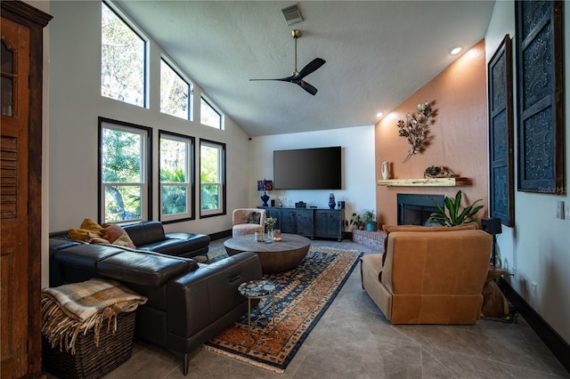 tiled living room featuring a textured ceiling, visible vents, a fireplace with raised hearth, a ceiling fan, and high vaulted ceiling