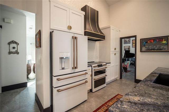 kitchen with white cabinets, dark stone countertops, custom exhaust hood, high end appliances, and a high ceiling