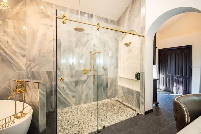 bathroom featuring tile walls, tile patterned floors, a marble finish shower, and a freestanding bath