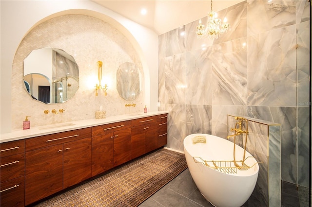 bathroom featuring tile patterned flooring, double vanity, tile walls, a chandelier, and a freestanding tub